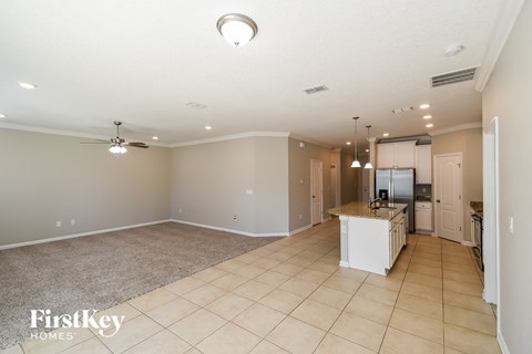 A spacious living room with a kitchen in the background.