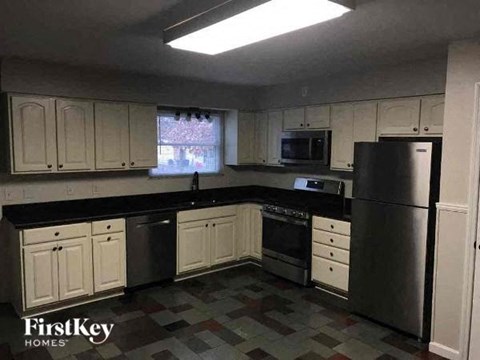 A kitchen with white cabinets and black countertops.