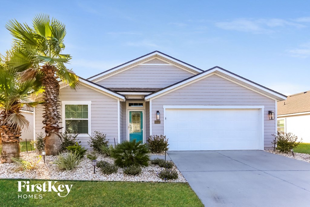 a white house with a white garage door and a palm tree