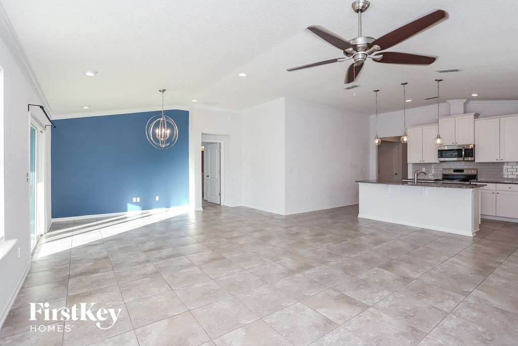 an empty living room with a blue accent wall and a ceiling fan
