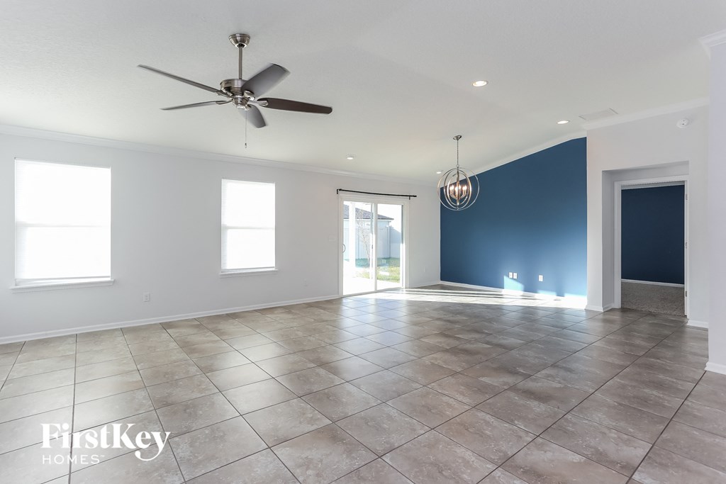 an empty living room with a ceiling fan and a blue accent wall