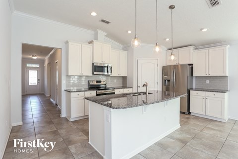 a large kitchen with white cabinets and a marble counter top