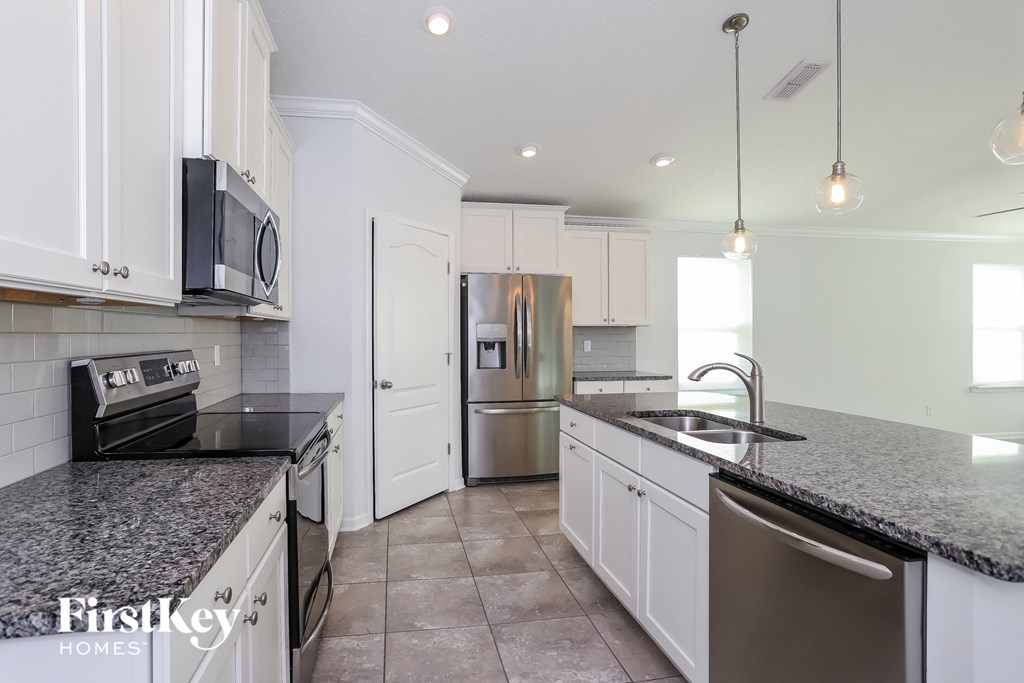 a white kitchen with granite counter tops and stainless steel appliances