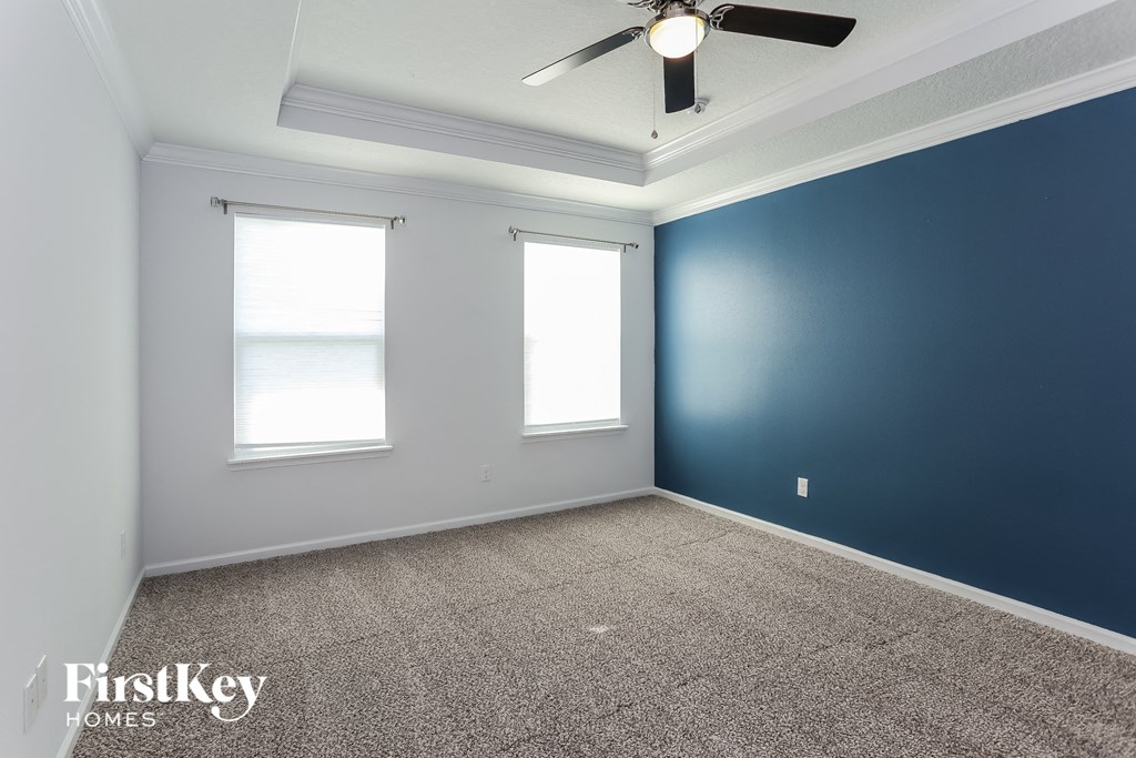 an empty room with a blue wall and a ceiling fan