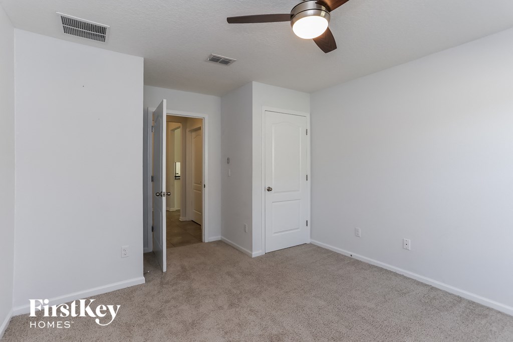 a bedroom with white walls and carpet and a ceiling fan
