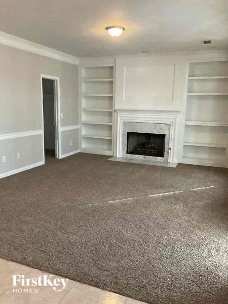 an empty living room with a fireplace and white shelves