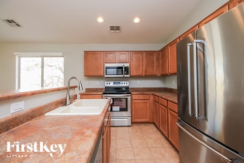 A kitchen with a stainless steel refrigerator and wooden cabinets.