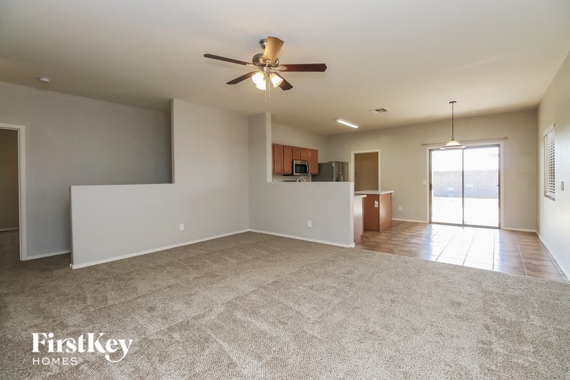 an empty living room and kitchen with a ceiling fan