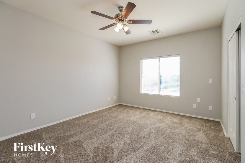 an empty living room with a ceiling fan and a window