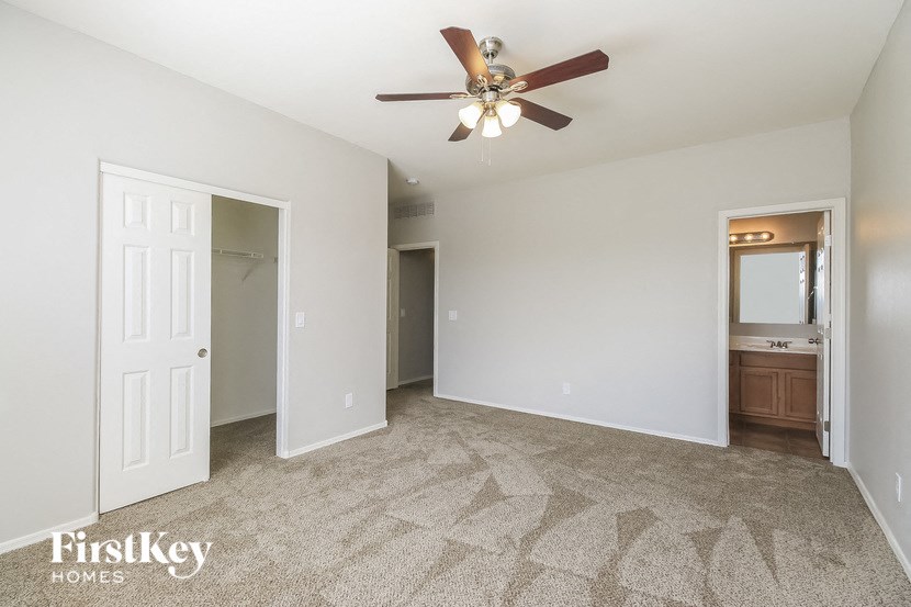 an empty living room with a ceiling fan and a closet