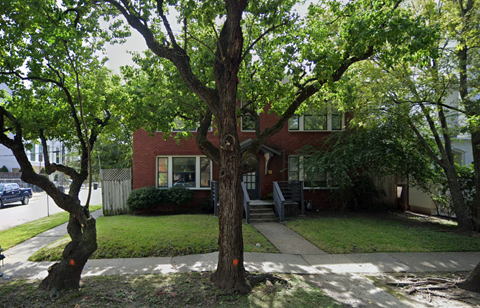 a red brick house with trees in front of it