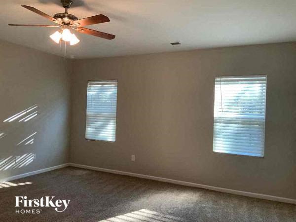 an empty room with a ceiling fan and two windows