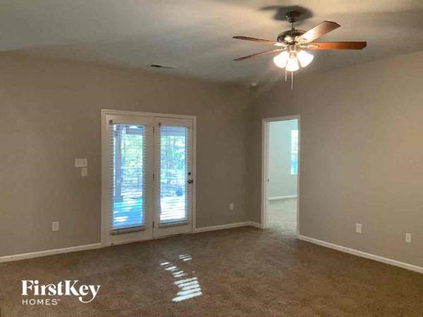an empty living room with a ceiling fan and a door