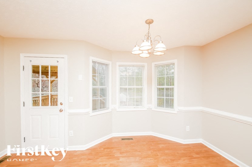 an empty dining room with a white door and windows