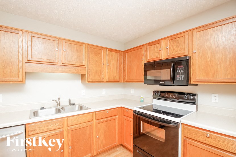 a kitchen with wooden cabinets and a stove and a microwave