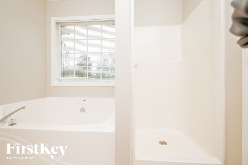 a white bathroom with a tub and a window