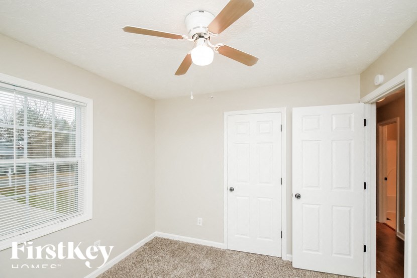 a bedroom with a ceiling fan and a door to a closet