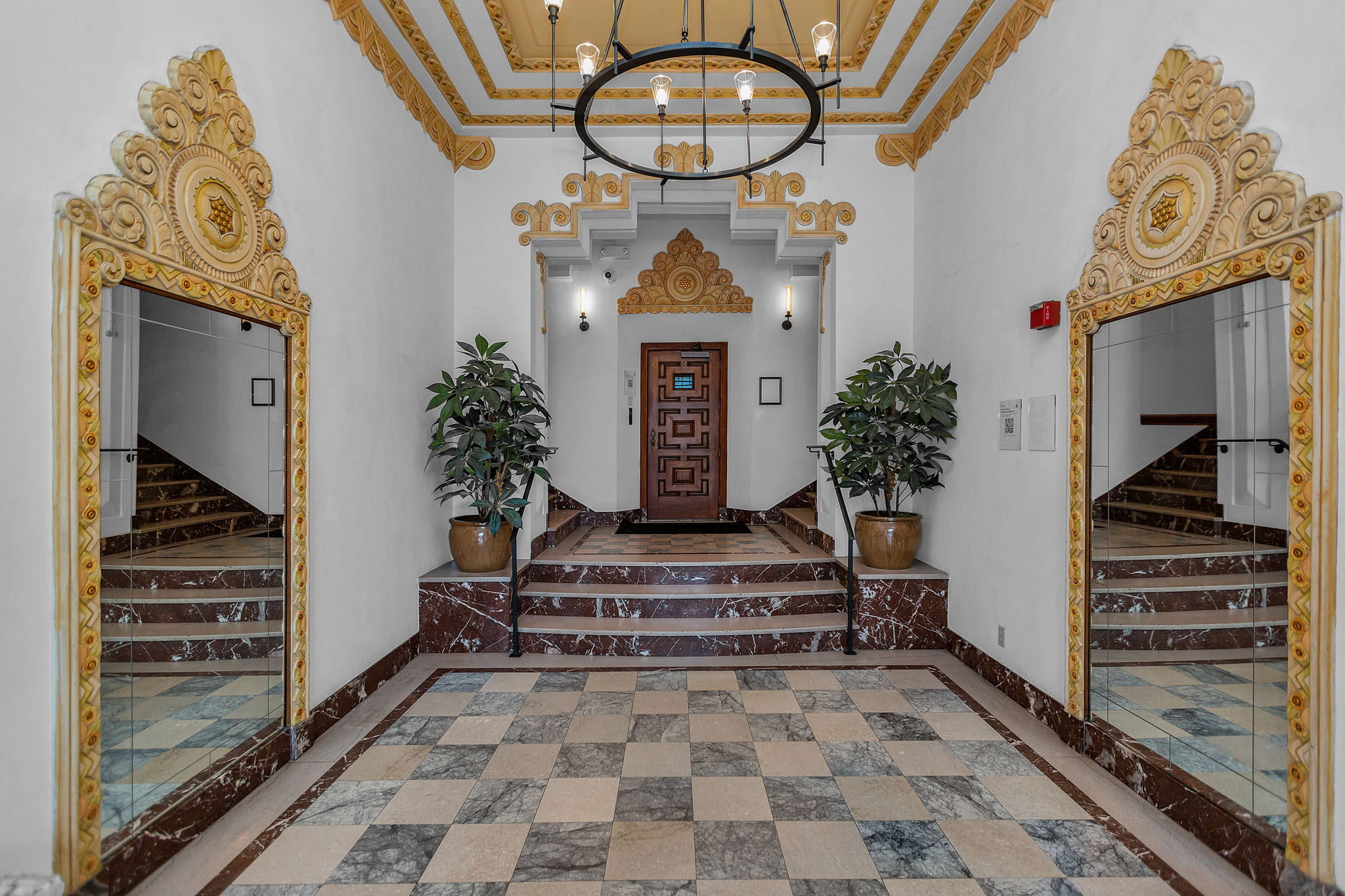 A hallway with a checkered floor and a chandelier.