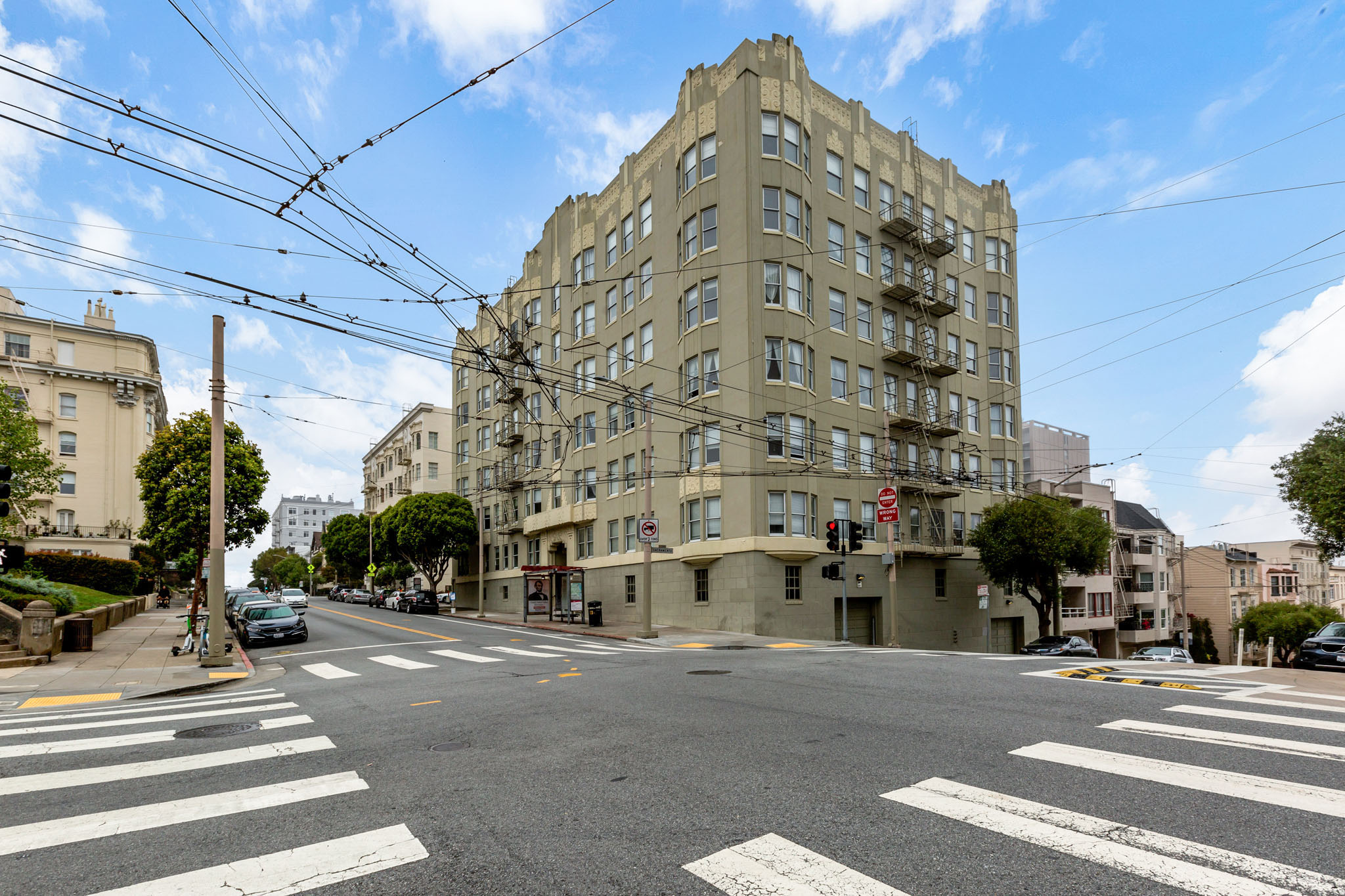 A street view of a city intersection with a large building in the background.