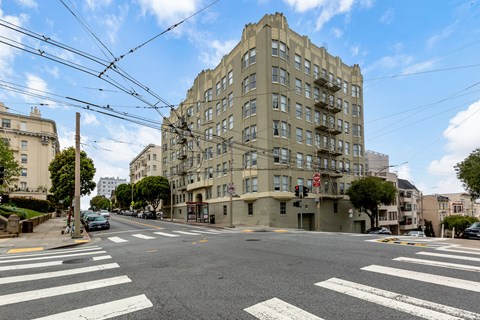 A street view of a city intersection with a large building on the corner.