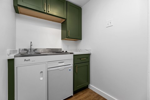A kitchen with green cabinets and white walls.