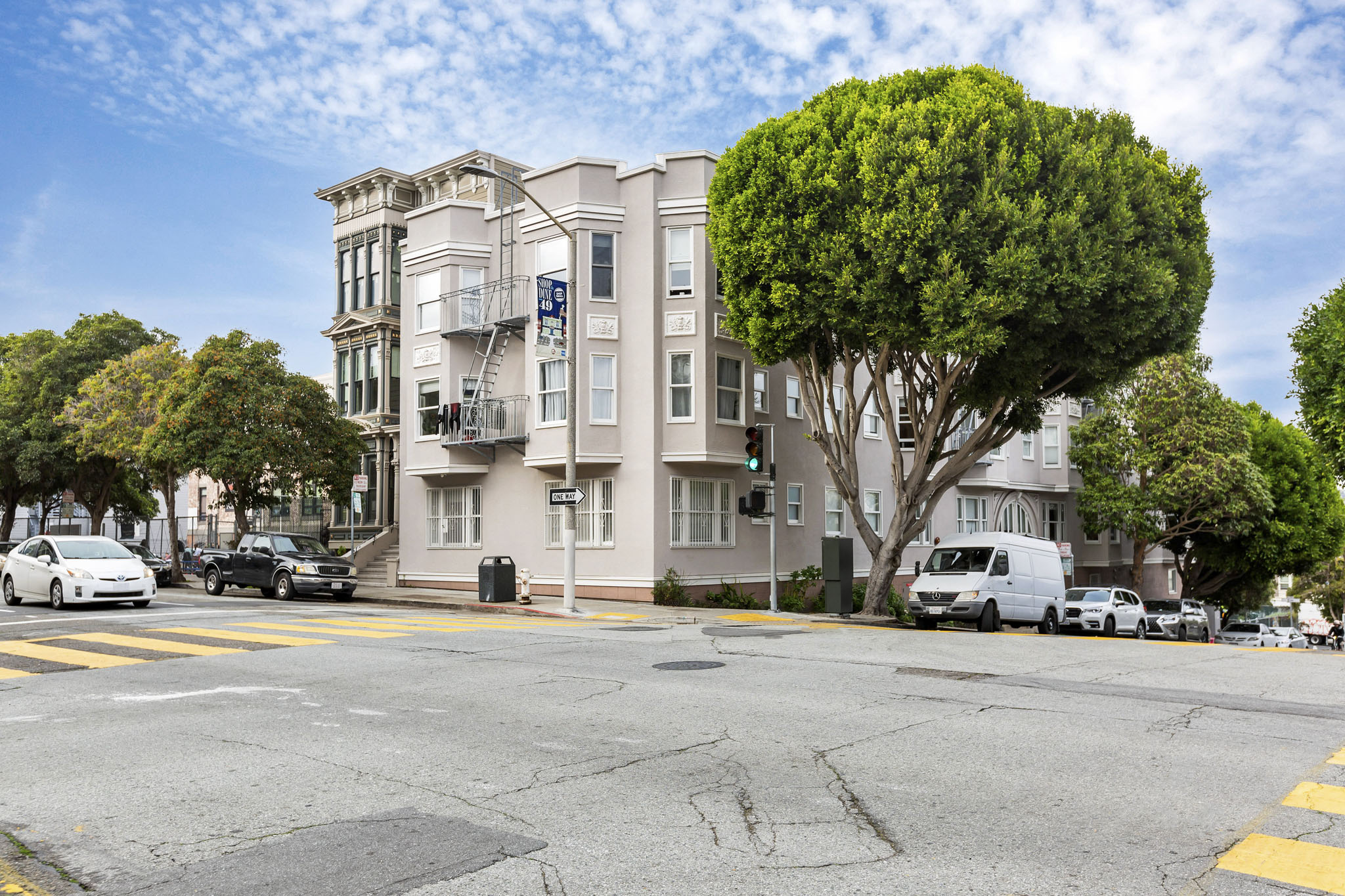 A street view of a residential area with cars parked on the side of the road.