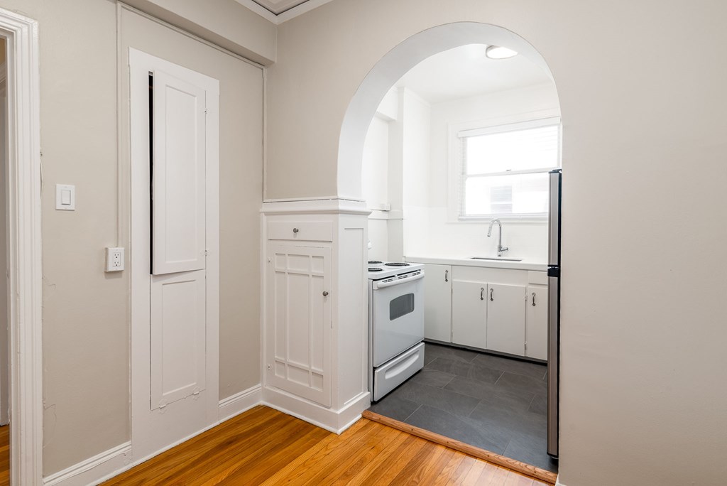 a kitchen with white cabinets and a stove and a window