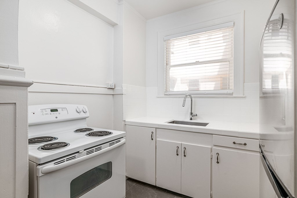 a white kitchen with white appliances and a window