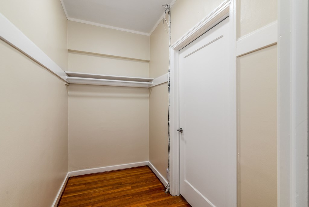 a bedroom with a door to a closet and a wood floor