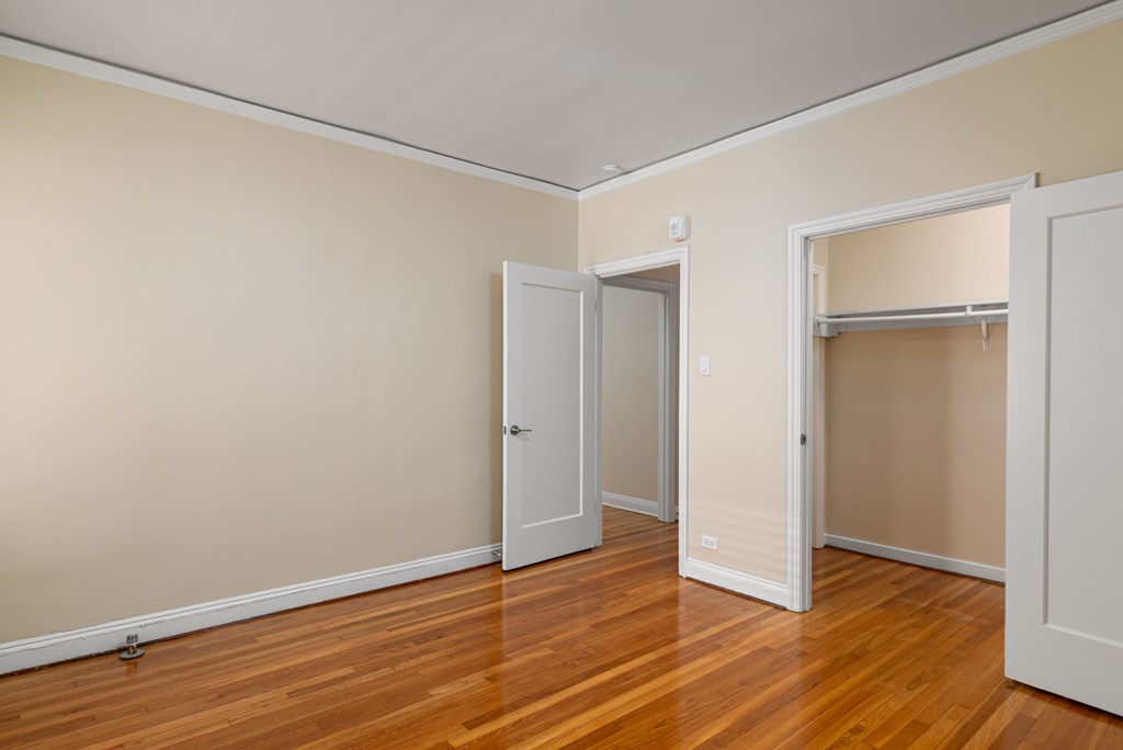 a bedroom with wood floors and white walls and a closet