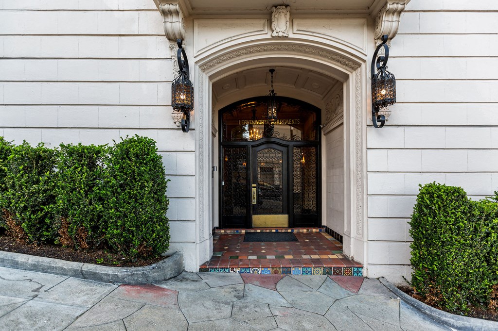A white building with a black door and two hanging lamps.