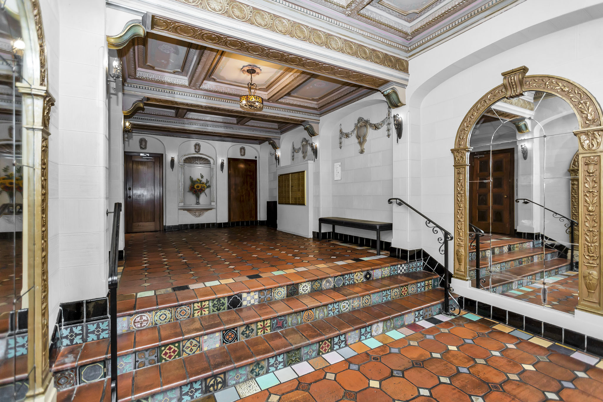 A staircase with a tiled floor and a mirror on the wall.