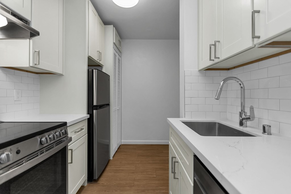 a kitchen with white cabinets and a sink and a stove