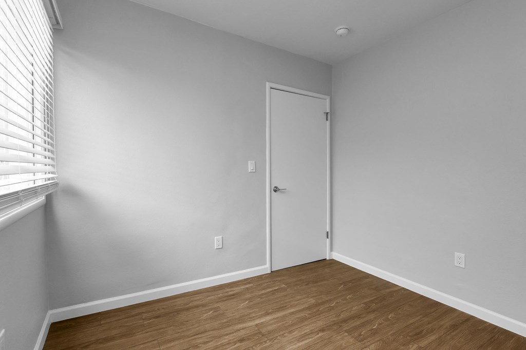 bedroom with white walls and wood flooring and a closet