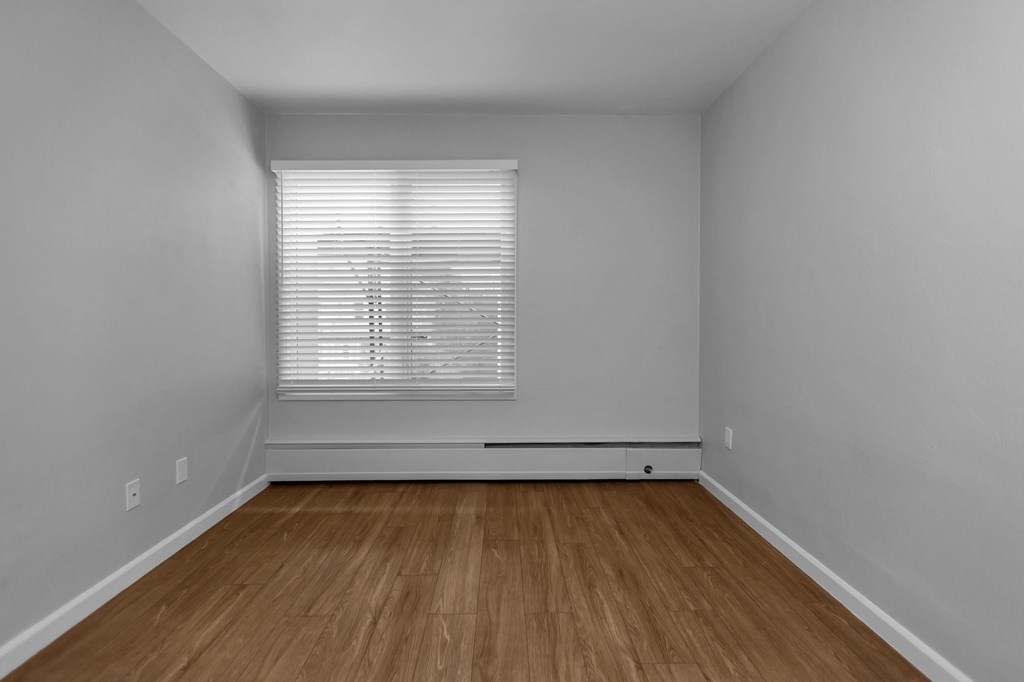 the living room of an empty house with wood floors and a window