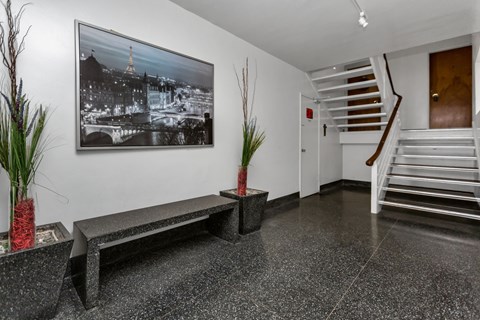 A black and white photo of a cityscape is hanging on a white wall above a bench.