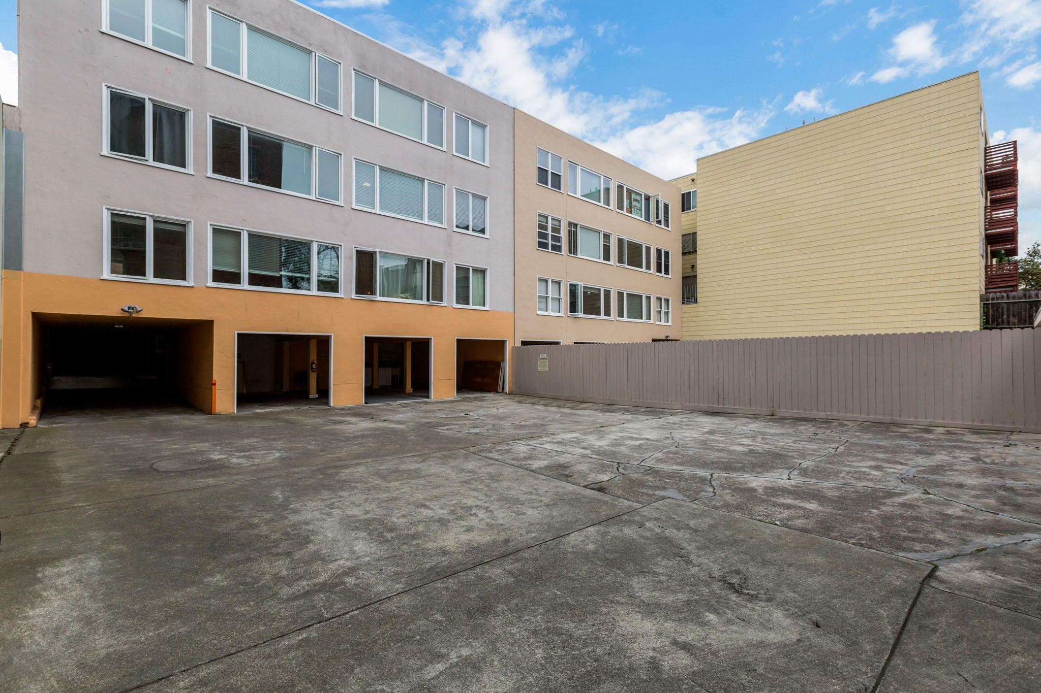 A large, empty parking lot in front of a building with a yellow wall.
