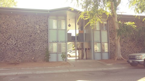 A building with a stone wall and a tree in front.