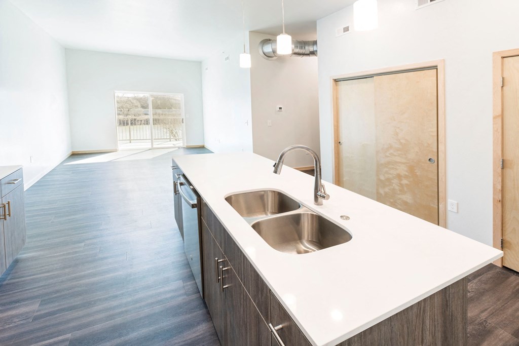 an empty kitchen with a stainless steel sink and white counter top