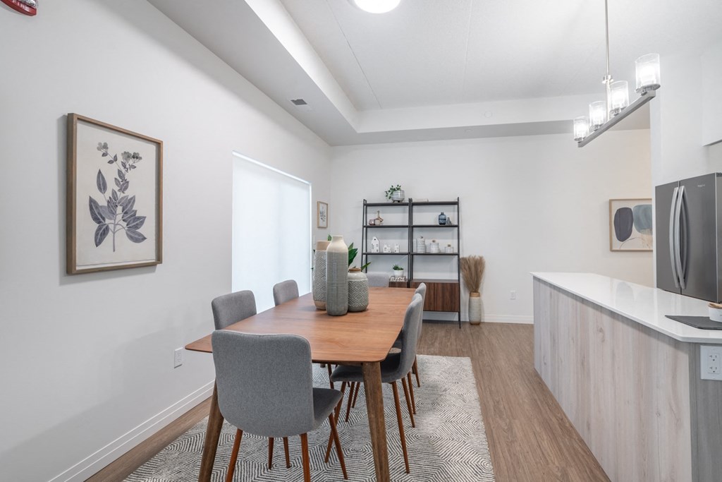 a dining area with a wooden table and chairs and a kitchen with a refrigerator