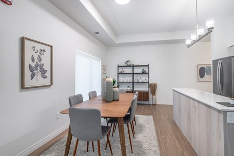 a dining area with a wooden table and chairs and a kitchen with a refrigerator