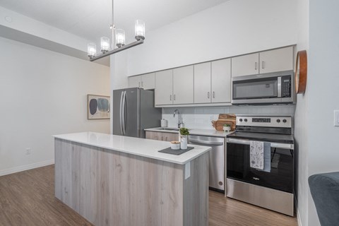an apartment kitchen with stainless steel appliances and white cabinets