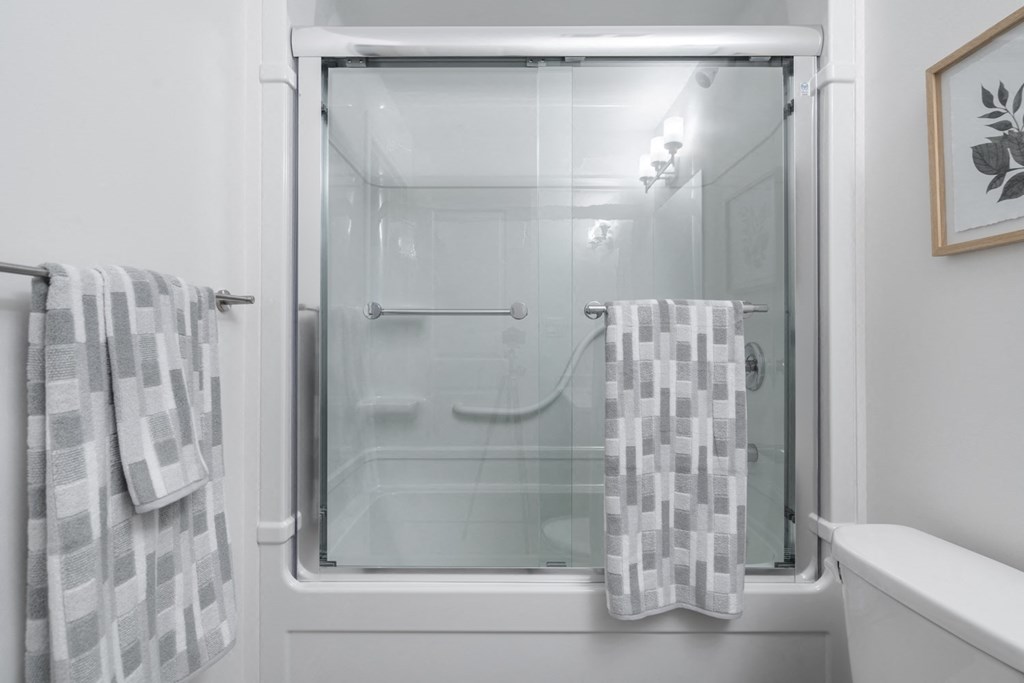 a white bathroom with a glass shower door and two towels