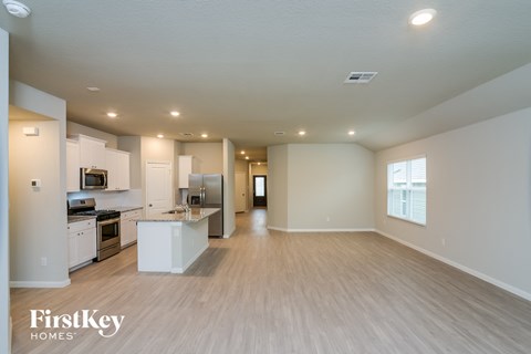 A spacious kitchen with white appliances and wooden flooring.