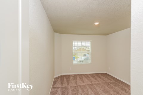 A room with a carpeted floor and a window showing a house and trees outside.