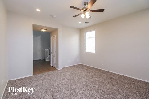 the spacious living room with ceiling fan and carpet