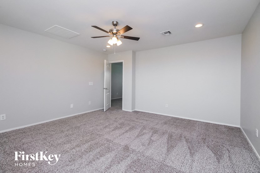the spacious living room with ceiling fan and carpeting