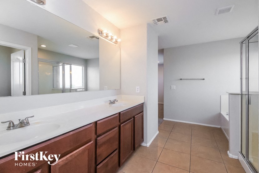 the master bathroom has a large vanity with two sinks and a shower