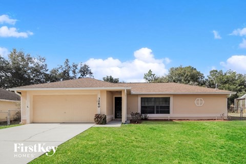 a beige house with a lawn and a driveway