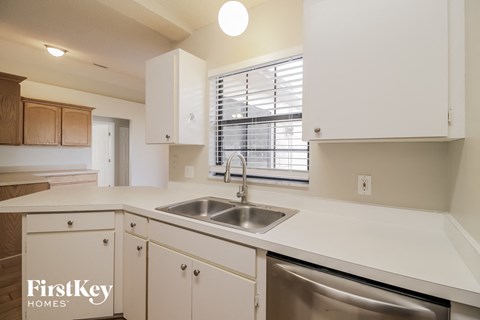 a kitchen with white cabinets and a sink and a window